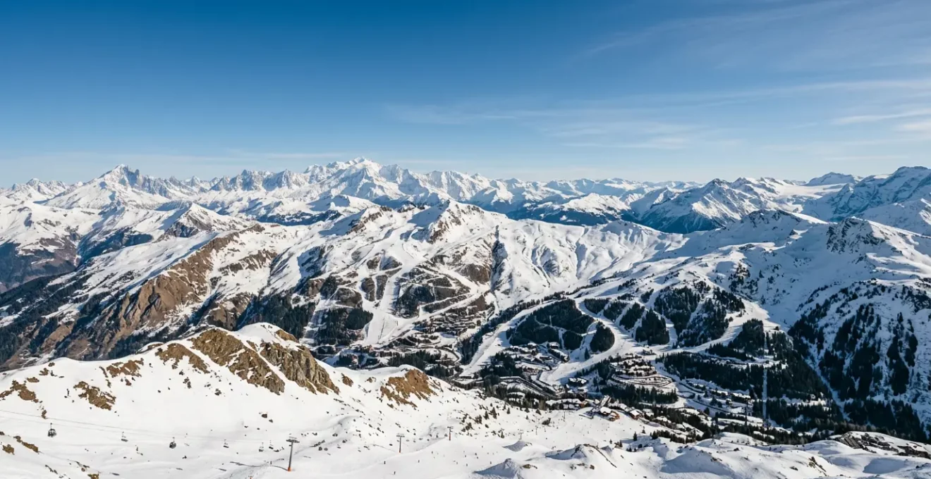 Panorama majestueux des sommets alpins enneigés sous un ciel bleu avec domaines skiables visibles