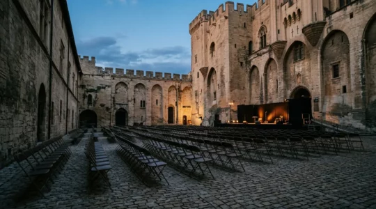 Scène de théâtre illuminée dans la cour d'honneur du Palais des Papes à Avignon lors du festival