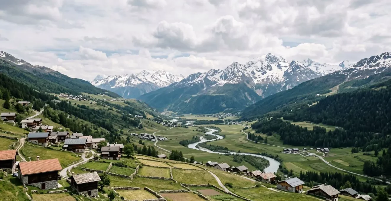Paysage de montagne dans les Alpes françaises avec vallée verdoyante et sommets enneigés au loin
