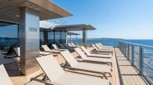 Pont extérieur d'un ferry moderne avec vue dégagée sur la mer Méditerranée, chaises longues vides alignées sous un ciel bleu éclatant
